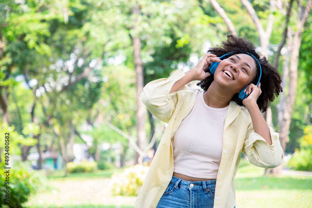Smiling charming African American woman in imagined dreaming while listening favorite songs during the leisure on the sunny meadow at park. Smiling charming African American woman in imagined dreaming while listening favorite songs during the leisure on the sunny meadow at park.