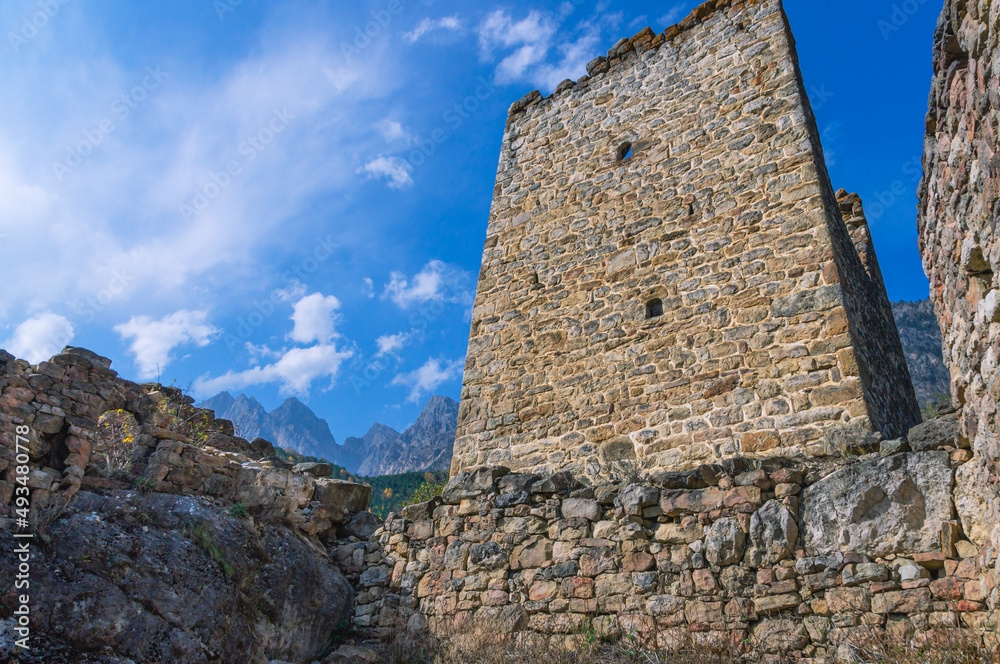 An abandoned medieval town. Military and residential ancient towers built of stones. Landscape in the mountains with a view of the ruins. The entrance to the fortress structure.