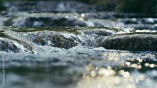 Clear stream running through stone boulders Abundant river flowing on stone bottom in slow motion. Wild mountain river water splashing in summer day.underwater bubbles. split view.. 4K. 1 photo