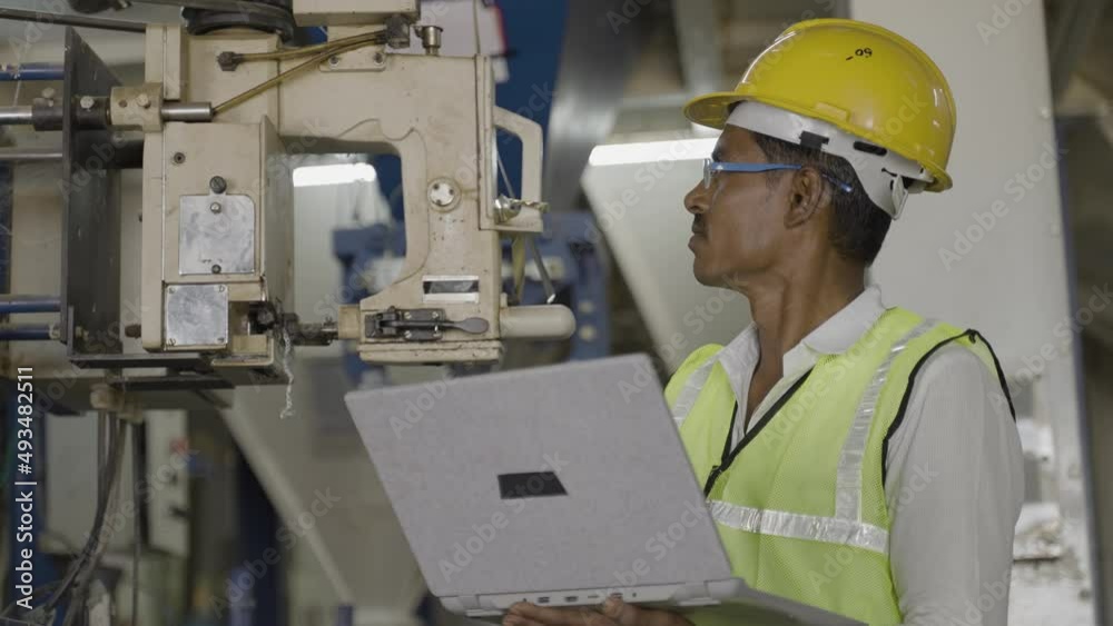 Handheld shot of industrial worker busy using laptop at workplace - concept of technology, safety and maintenance engineer Handheld shot of industrial worker busy using laptop at workplace - concept of technology, safety and maintenance engineer