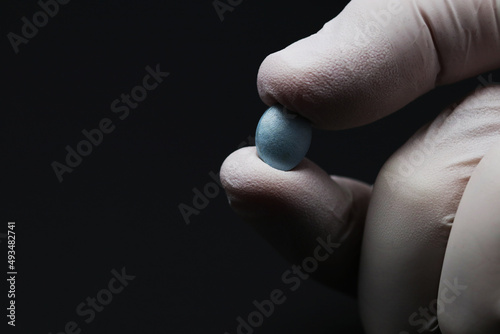 Doctor's hand holding a blue pill in the fingers