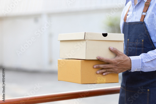 Close-up, the delivery man holding the parcel is handing it to the recipient.