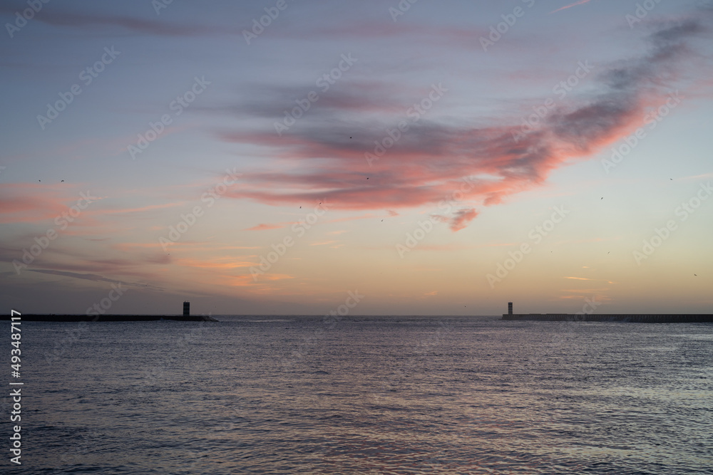 Beautiful sunset on the sea with two breakwaters in the background.