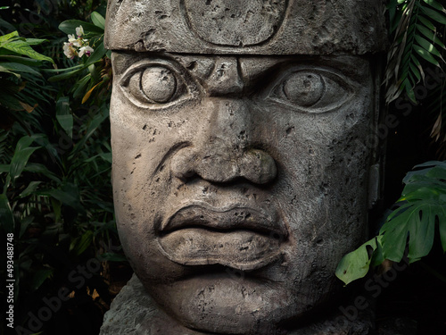 Olmec sculpture carved from stone. Mayan symbol - Big stone head statue in a jungle photo