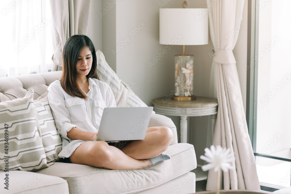 Happy asian woman using laptop at home living room ,relaxing ,e-learning ,working concept. Happy asian woman using laptop at home living room ,relaxing ,e-learning ,working concept.