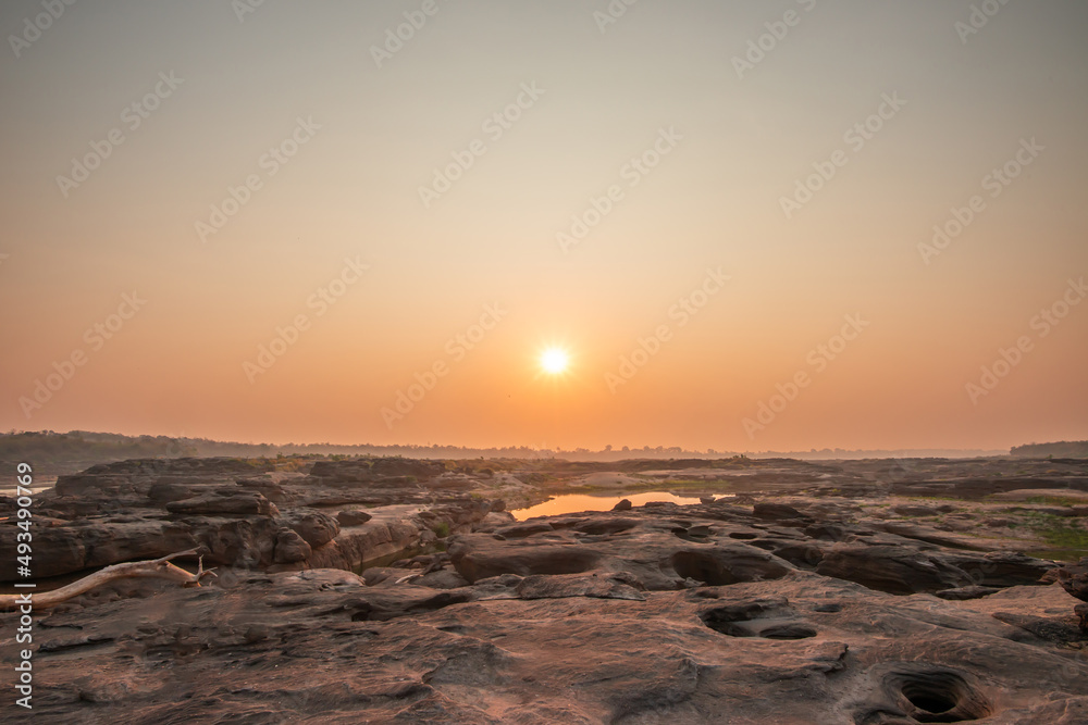 Sunrise at three thousand waved rocks under the natural sandstone group of the Mekong River that has been eroded for a long time in Ubon Ratchathani, Thailand.