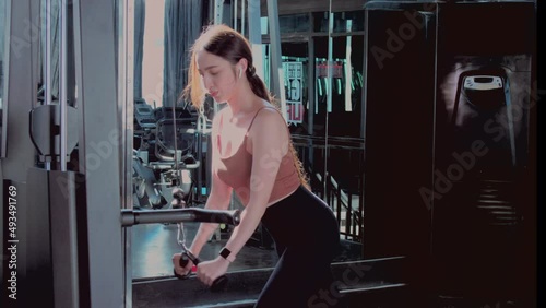 Woman doing fitness and strength training for the triceps on the cable in the fitness center. Asian fit girl doing warm up her triceps on the cable machine. Healthy lifestyle concept.