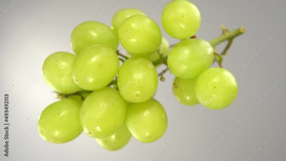 Green grapes fall on the glass surface, bottom view. Green grapes fall on the glass surface, bottom view.