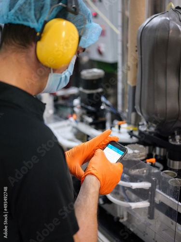Worker using the mobile while standing in a brewery