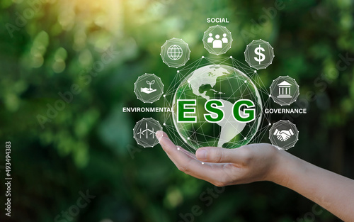 ESG icon concept in the hand for environmental, social, and governance in sustainable and ethical business on the Network connection on a green background.