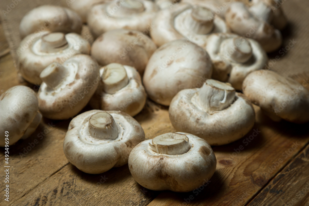 Champignons on a wooden background. Fresh white mushrooms. A lot of mushrooms Champignons on a wooden background. Fresh white mushrooms. A lot of mushrooms