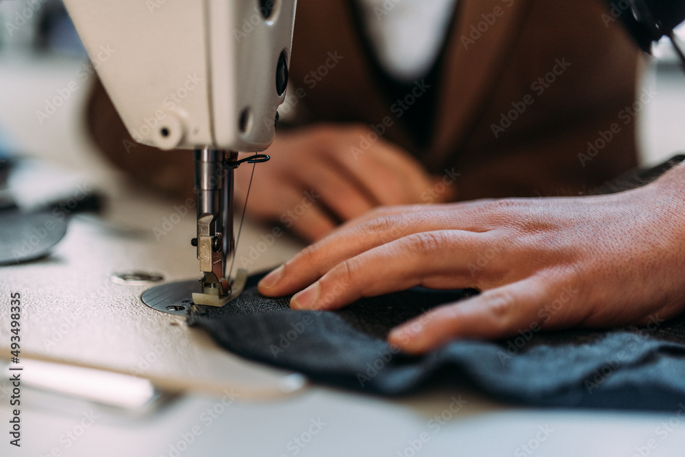 Maßschneider mit Nähmaschine bei der Arbeit horizontal