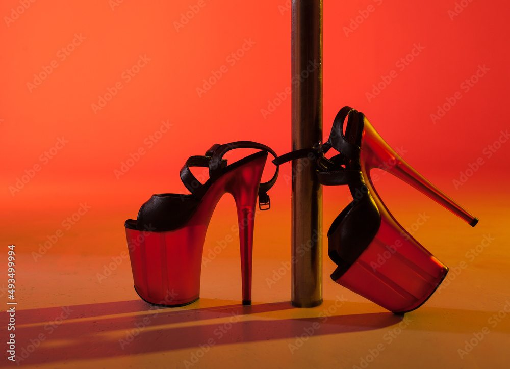 Shoes for a strip, pole dance in heels near the pylon on a red-yellow background - obrazy, fototapety, plakaty 