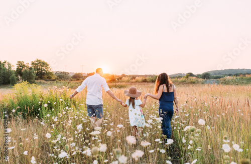 Fototapeta Naklejka Na Ścianę i Meble -  Familie rennt freudig über eine wiese im sommer horizontal