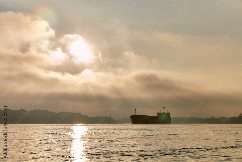 Silhouette of a ship on the roadstead in the Danube river against the background of clouds