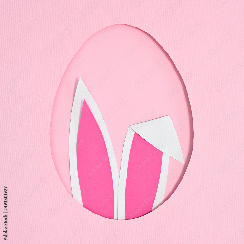 Egg shape frame with rabbit ears peek from hole on pastel pink background. Flat lay creative Easter concept