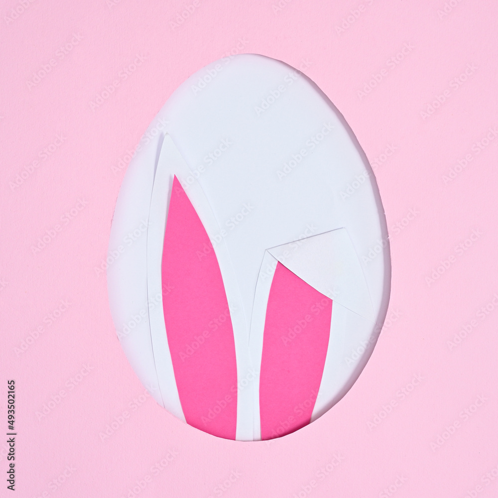 Easter creative concept. Egg shape with bunny ears on pastel pink background. Flat lay