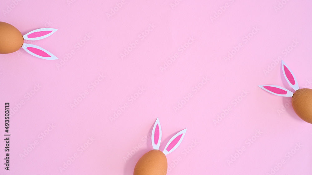 Creative copy space backround with natural eggs with rabbit ears on pastel pink theme. Flat lay Easter concept