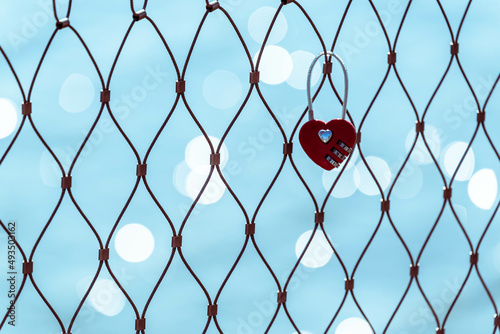 Red heart shaped padlock on a fence conceptual love forever.