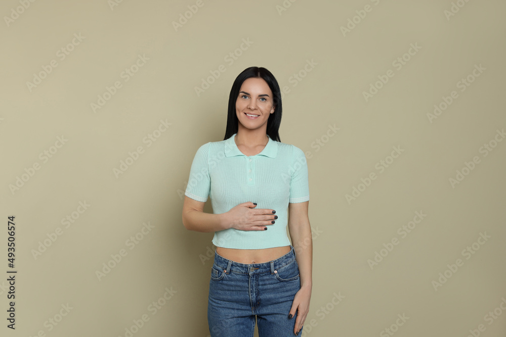 Happy woman touching her belly on beige background. Concept of healthy stomach Happy woman touching her belly on beige background. Concept of healthy stomach