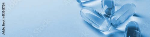Fish oil softgels. Vitamins and healthy lifestyle. Blue tinted banner or headline. Softgel closeup. Medicines and nutritional supplements. Macro