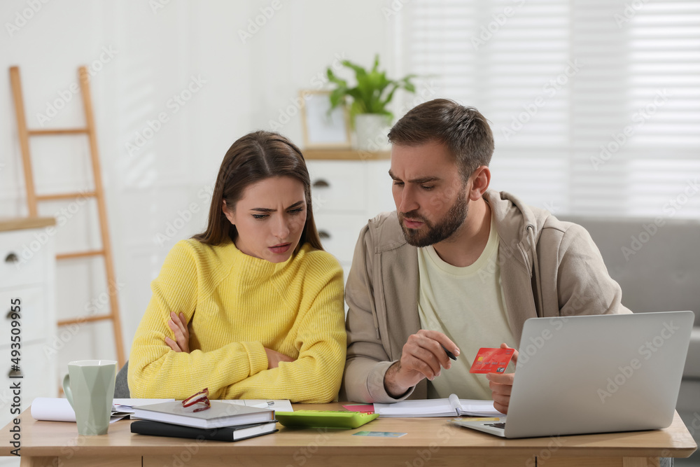 Young couple discussing family budget at table in living room Young couple discussing family budget at table in living room