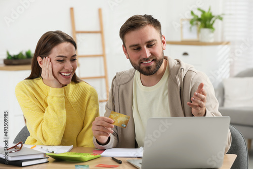 Young couple discussing family budget at table in living room © New Africa