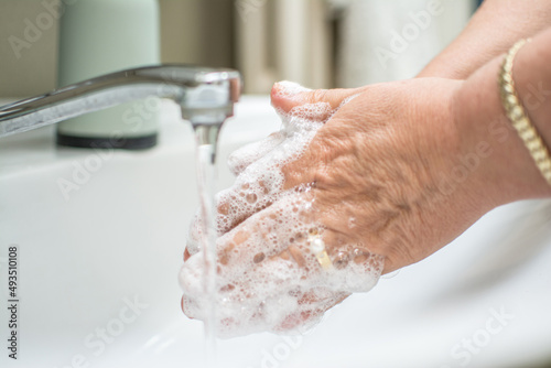 Obraz na płótnie Close up of senior woman's hands washing hands using soap