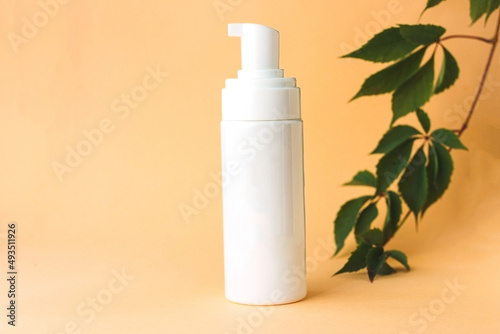White mock-up bottle of cream with green leaves