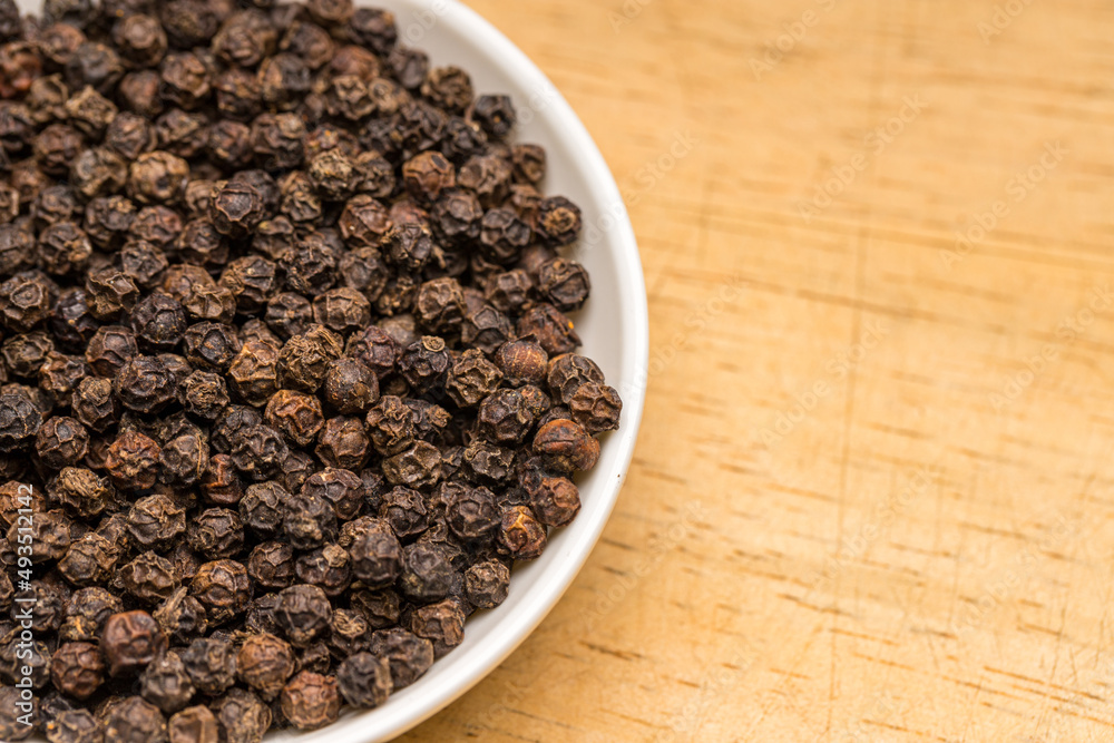 Black pepper in a white bowl on wooden table Black pepper in a white bowl on wooden table
