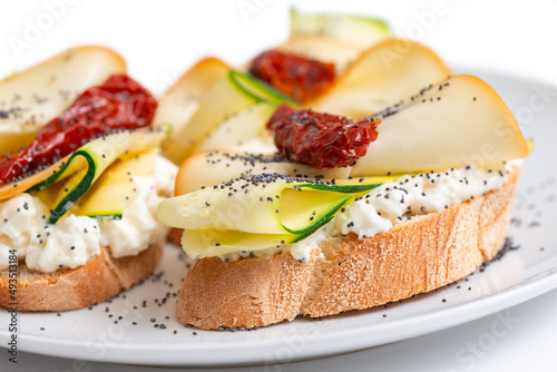 Deliziosi crostini conditi con stracchino, zucchine, pomodori secchi e scamorza, antipasti italiani 