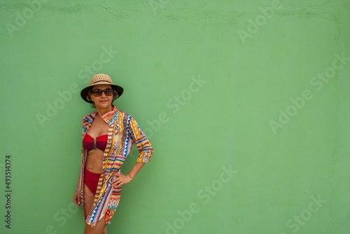 Woman wearing swimming wear leaning against a Green Wall