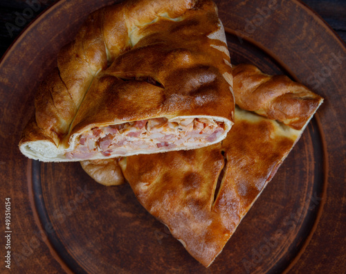 Delicious rustic meat pie. Homemade pie lies on a clay plate.