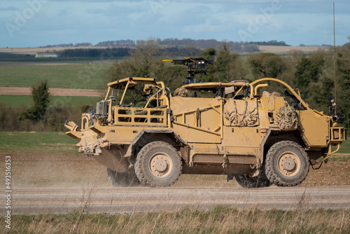 British army Supacat Jackal 4x4 rapid assault, fire support and reconnaissance vehicle in action across open countryside on a military battle training exercise