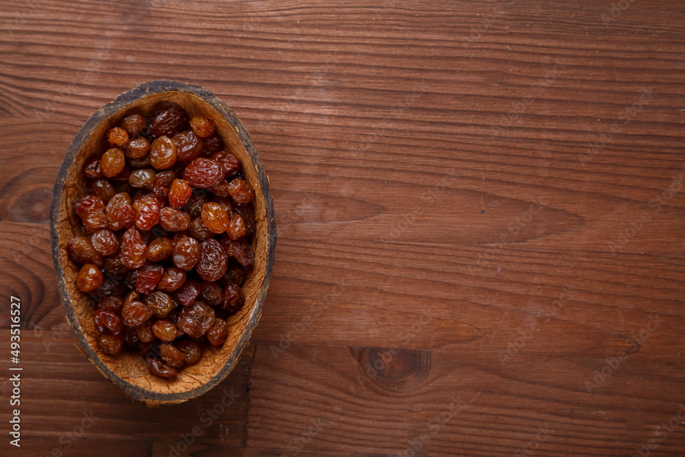 Raisins in a bowl of coconut shell on a wooden table.copy space Raisins in a bowl of coconut shell on a wooden table.copy space