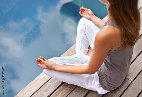 Calmness of the still waters. Cropped closeup of a young woman meditating poolside.