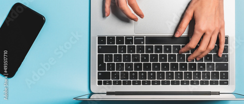 Overhead view of the working woman hands typing on keyboard notebook laptop computer at the colorful background office desk