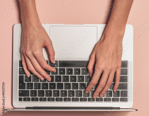 Overhead view of the working woman hands typing on keyboard notebook laptop computer at the colorful background office desk