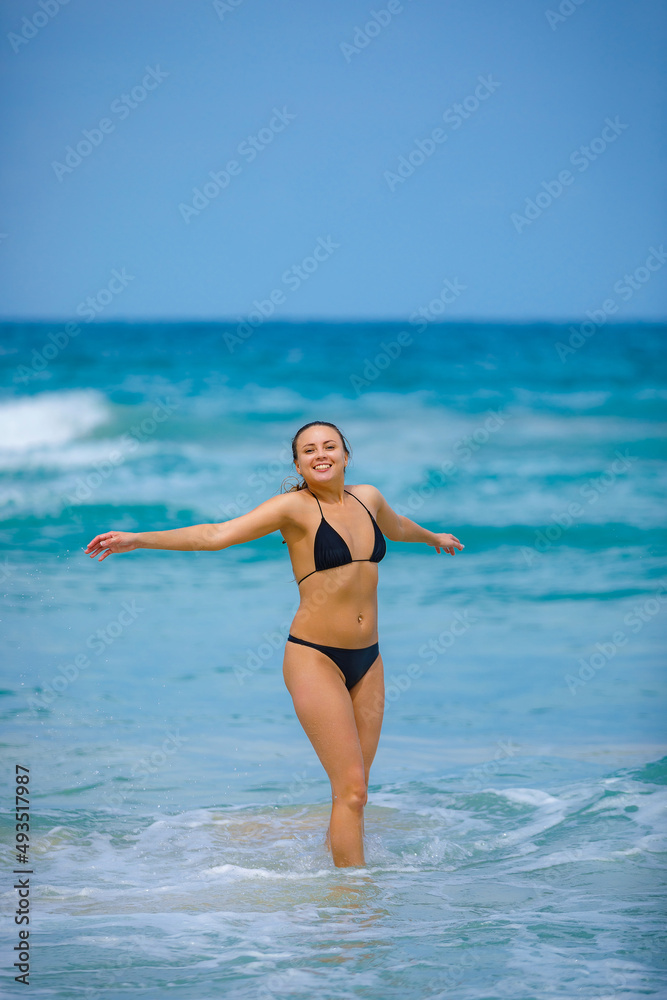A young girl in a green bathing suit stands by the sea and laughs with her arms outstretched. High quality photo A young girl in a green bathing suit stands by the sea and laughs with her arms outstretched. High quality photo