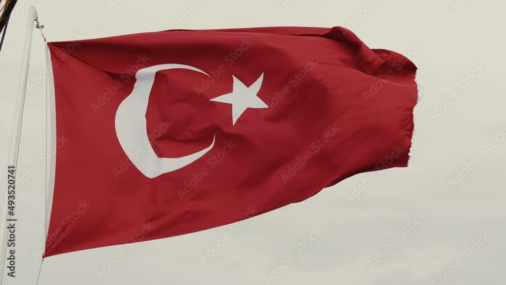 Low angle close-up of beautiful Turkey flag, country symbol waving on pole in strong wind on grey cloudy sky background. Low angle close-up of beautiful Turkey flag, country symbol waving on pole in strong wind on grey cloudy sky background.
