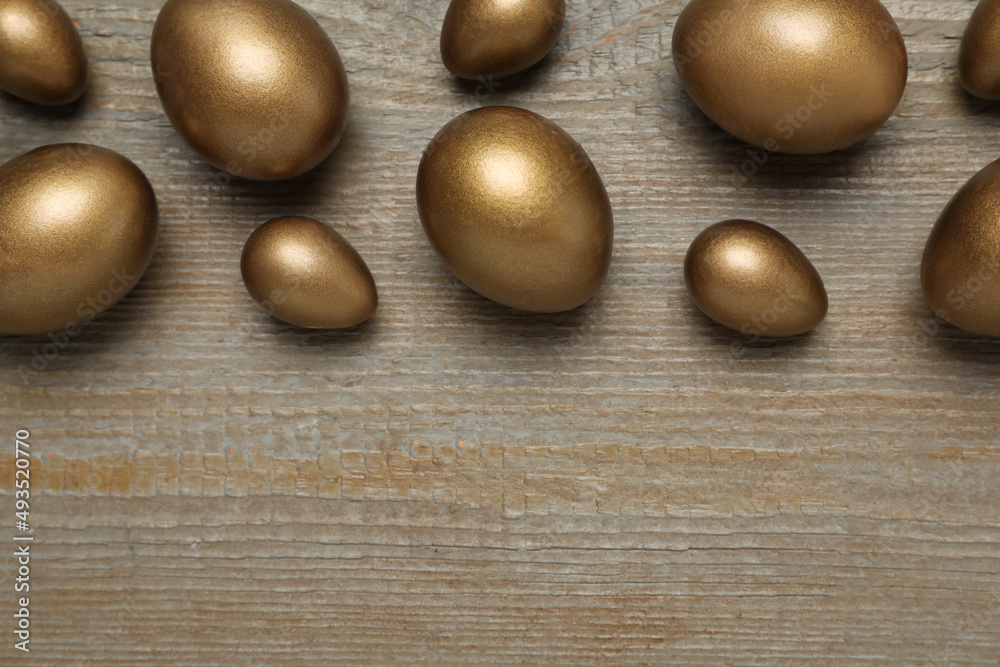 Golden eggs on wooden table, flat lay. Space for text Golden eggs on wooden table, flat lay. Space for text
