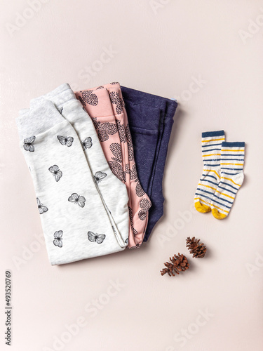 Flat lay of girl's joggers and sock on pink background