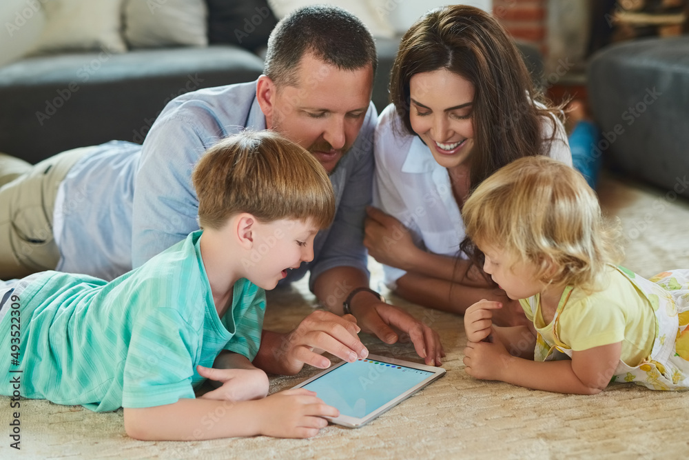 Using apps together as a family. Cropped shot of a young family using a tablet together on the floor in the living room at home. Using apps together as a family. Cropped shot of a young family using a tablet together on the floor in the living room at home.