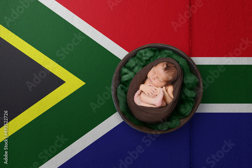 Newborn portrait on background in color of national flag. Patriotic photography concept. South Africa photo