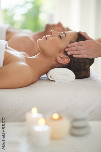 Enjoying a day of pampering. A husband and wife lying together on massage tables and receiving head massages.