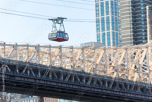 Roosevelt Island Tramway runs beside the Queensboro Bridge toward the high-rise residential building in Midtown Manhattan from Roosevelt Island on November 2021 New York City NY USA. 