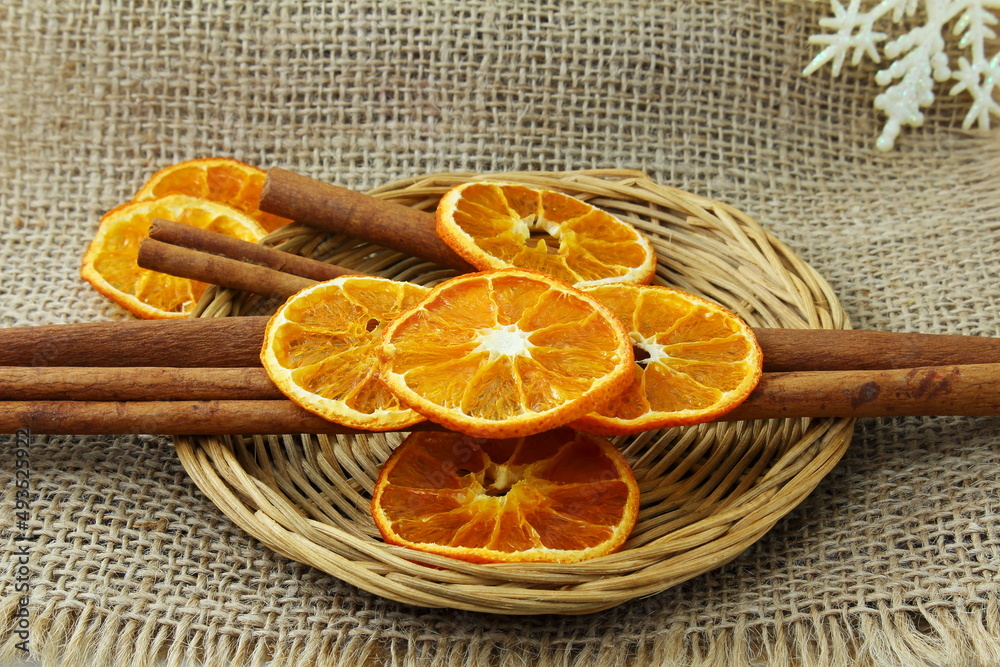 dry orange citrus fruits slice with cinnamon stick for snack,decoration,food,health,christmas related concept on jute fabric background dry orange citrus fruits slice with cinnamon stick for snack,decoration,food,health,christmas related concept on jute fabric background