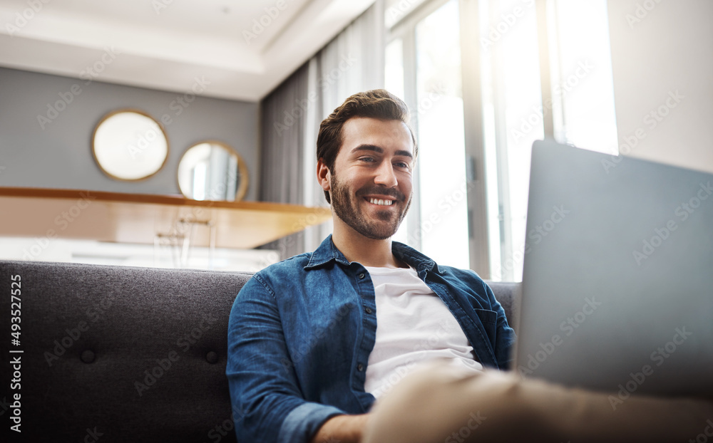 Theres always some cool stuff to watch on the internet. Shot of a handsome young man using his laptop while relaxing on a sofa at home. Theres always some cool stuff to watch on the internet. Shot of a handsome young man using his laptop while relaxing on a sofa at home.