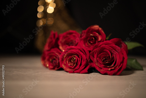 
Beautiful photo of a beautiful bouquet of red roses with a golden coating on the petals on a black background with golden bokeh, date surprise