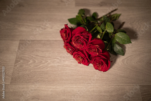 beautiful photo of a beautiful bouquet of red roses with golden pollination on the petals on the background of a wooden floor, a gift for a girl on a date, valentine's day, anniversary
